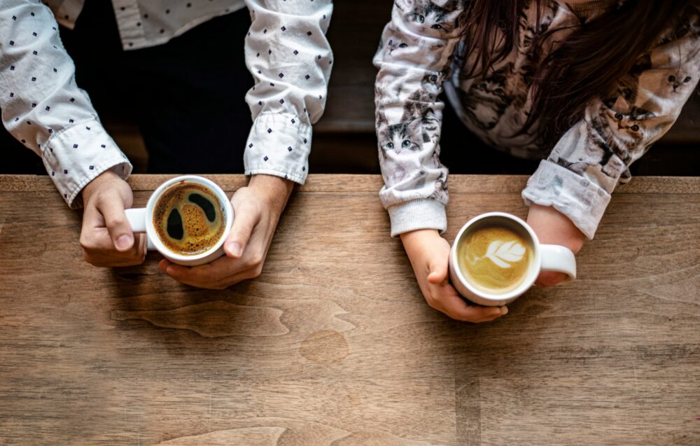テーブルの上でコーヒーカップを持つ二人