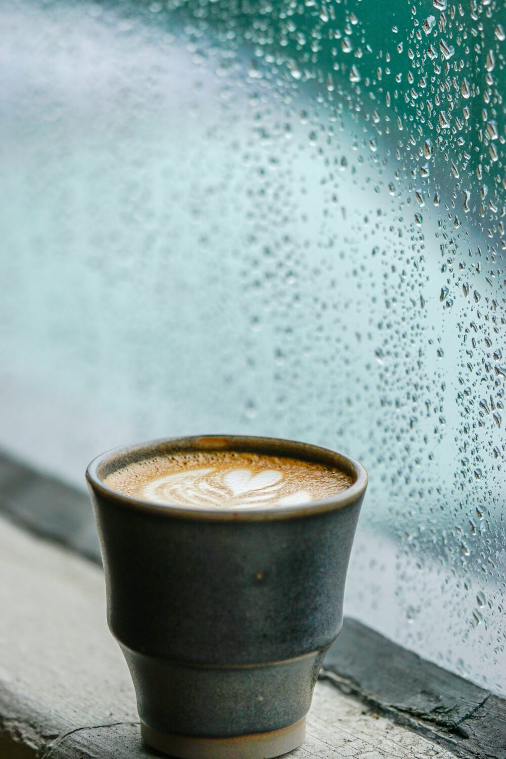 雨に濡れた窓際に置いてあるコーヒー